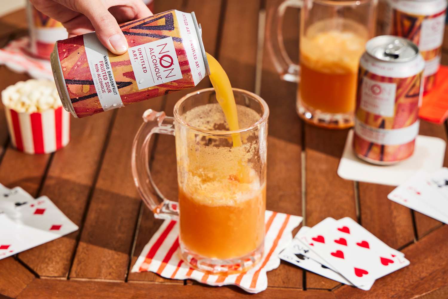 a hand pouring a can of untitled art's mango dragonfruit fruited sour
