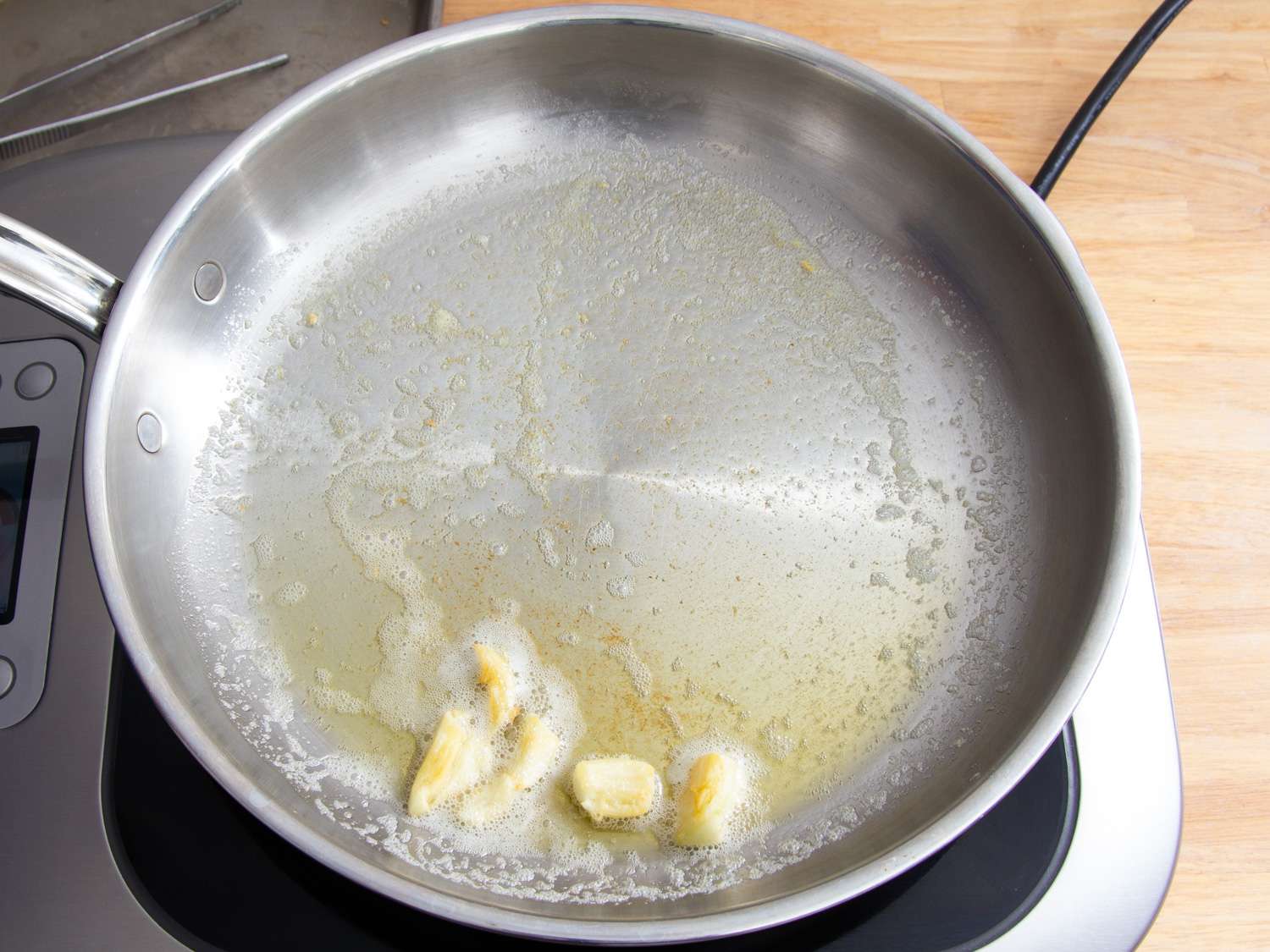 Warming garlic cloves in butter in a skillet.