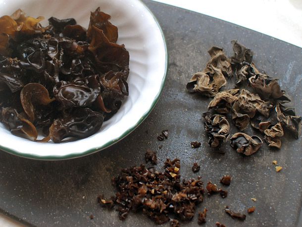 Wood ear mushrooms on a cutting board: dried, rehydrated in bowl, and chopped into small pieces.