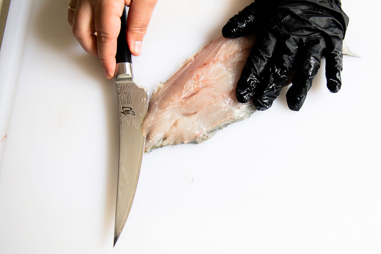 A person using the Shun Classic 6" Boning & Fillet Knife to slice a fish