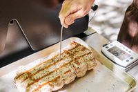 Person inserting the needle of ThermoWorks Smoke Remote BBQ Alarm Thermometer in a grilled piece of chicken