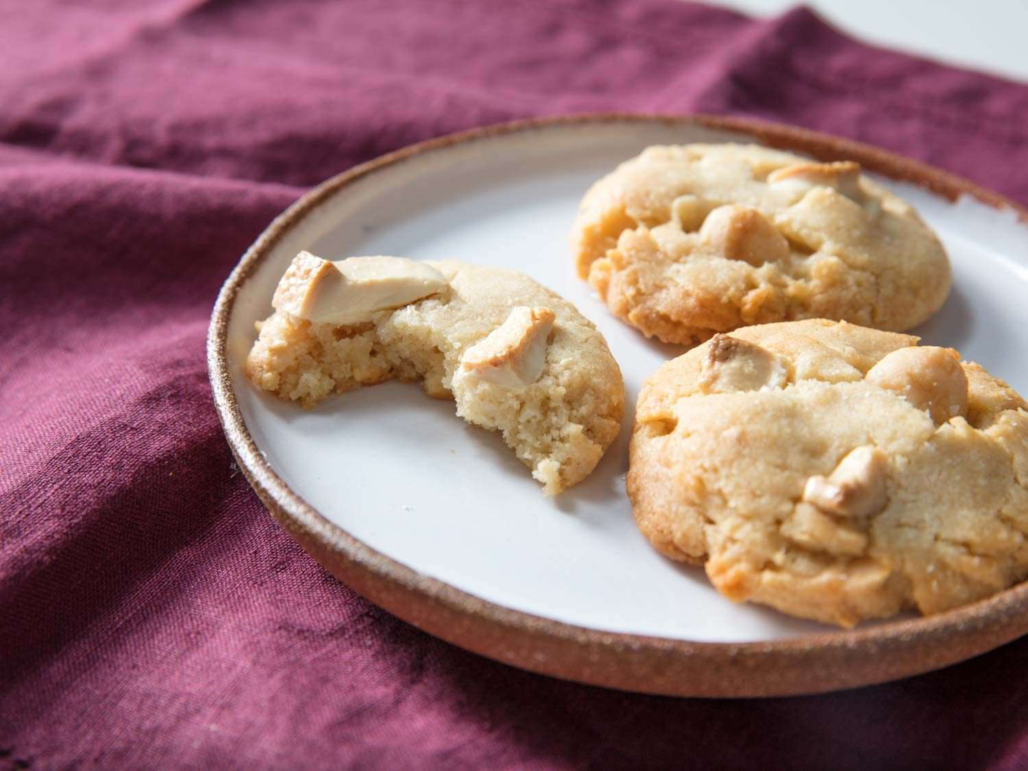 White chocolate macadamia nut cookies with a bite taken out.