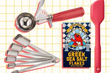 A set of kitchen tools including stainless steel measuring spoons an ice cream scoop a spatula and a box of Greek sea salt flakes