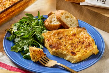 A plate with a serving of eggbased casserole side salad and slices of bread