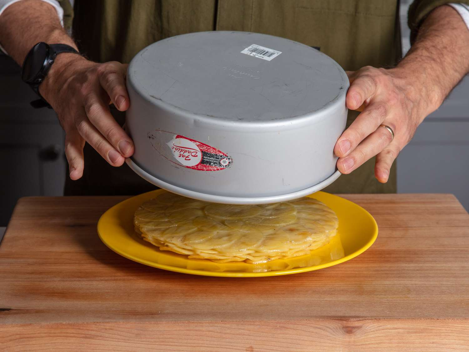Unmolding the potato cake from the cake pan onto a plate.