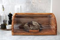 The Williams Sonoma bread box with a boule inside of it.