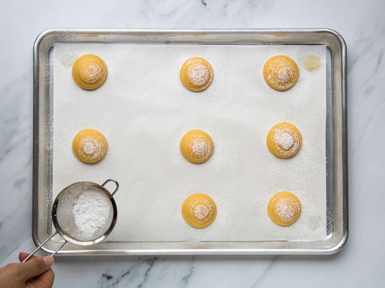 choux pastry puffs pre-bake being sprinkled with powdered sugar