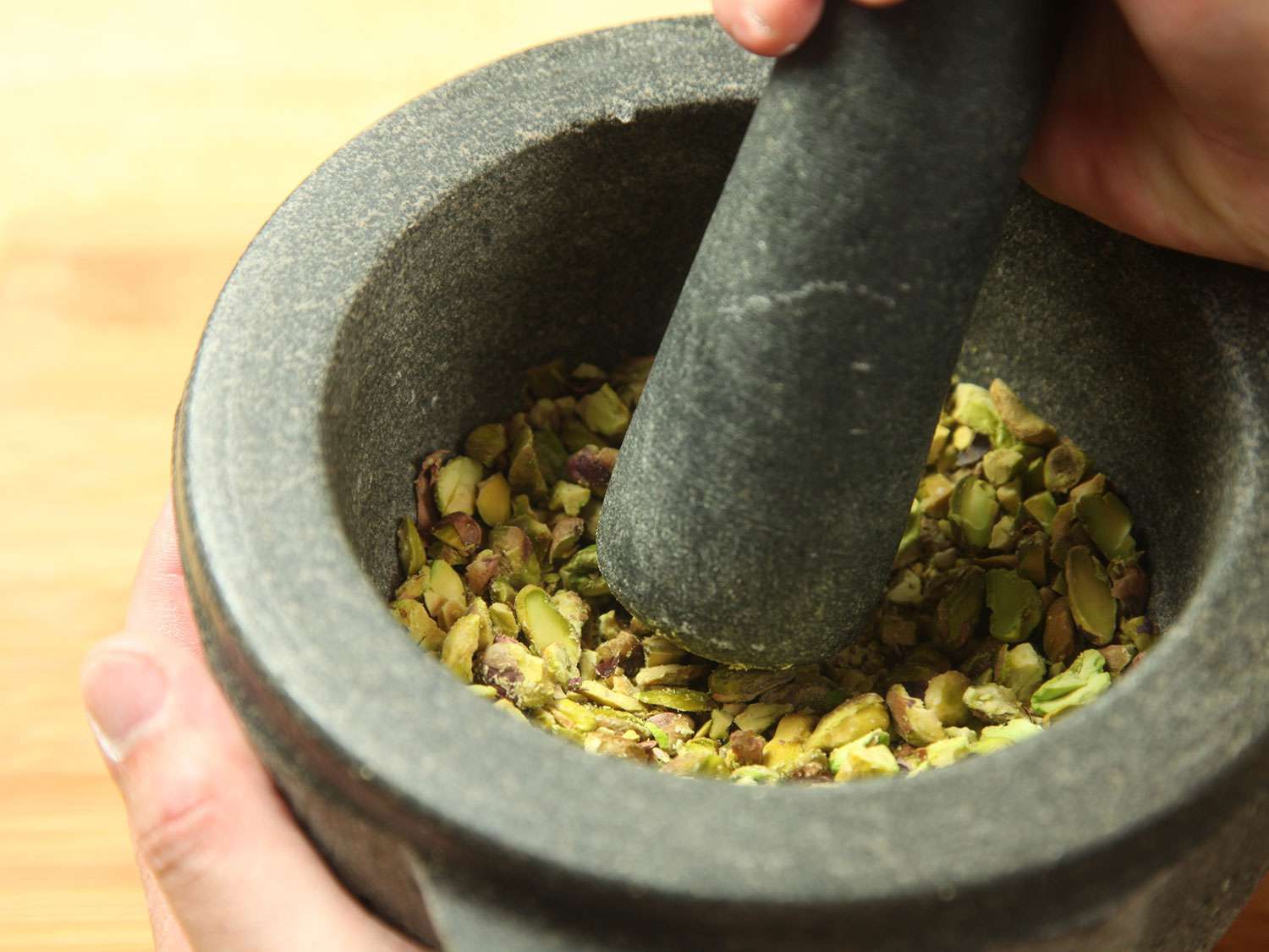 Grinding pistachios with pestle and mortar for beet citrus salad.