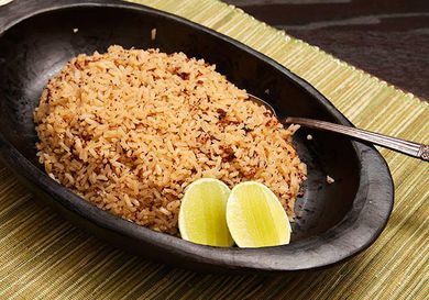 A dish of arroz con coco garnish with two lemon wedges