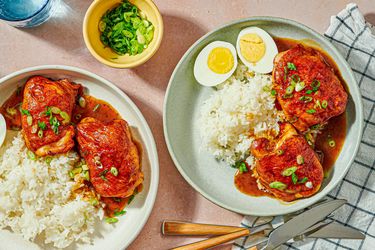 Roast chicken served with rice sauce and garnished with green onions on plates a halved boiled egg included on one plate