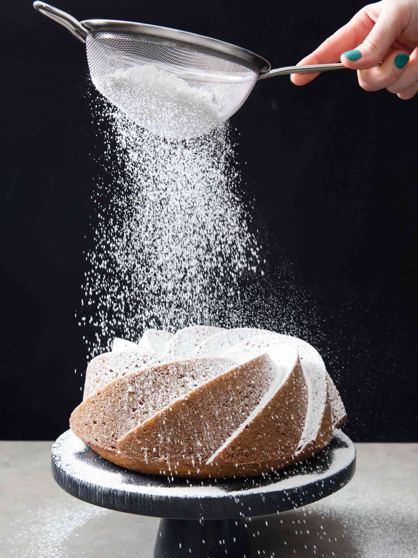 Dusting a homemade bundt cake with powdered sugar.