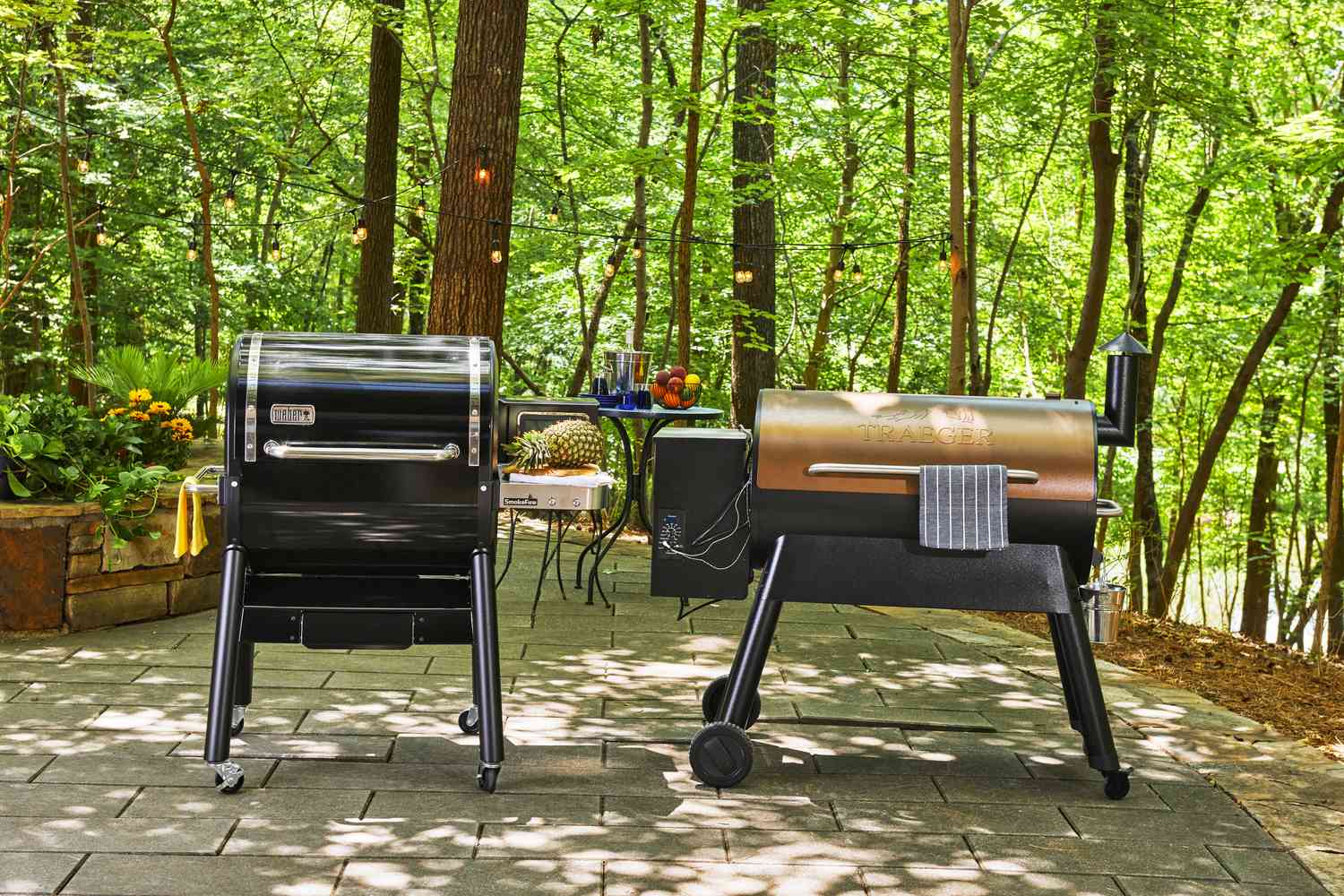 two pellet grills beside each other on a stone patio