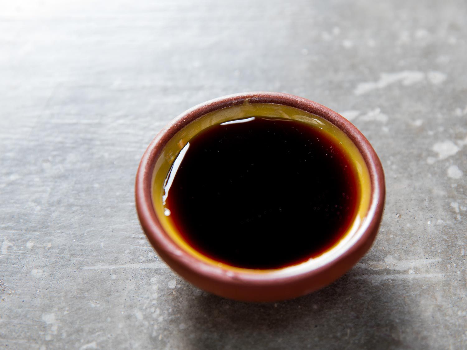 Small bowl of soy sauce on grey countertop