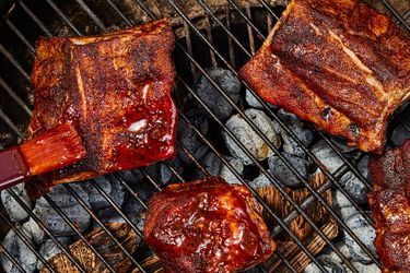 Barbecue ribs and meat on a grill with sauce being applied