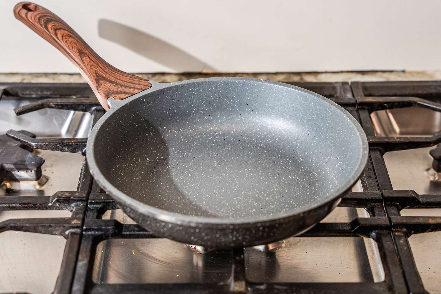 A wooden-handled nonstick pan on a gas stove