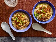 Overhead view of two bowls of congee on a brown woven placemat