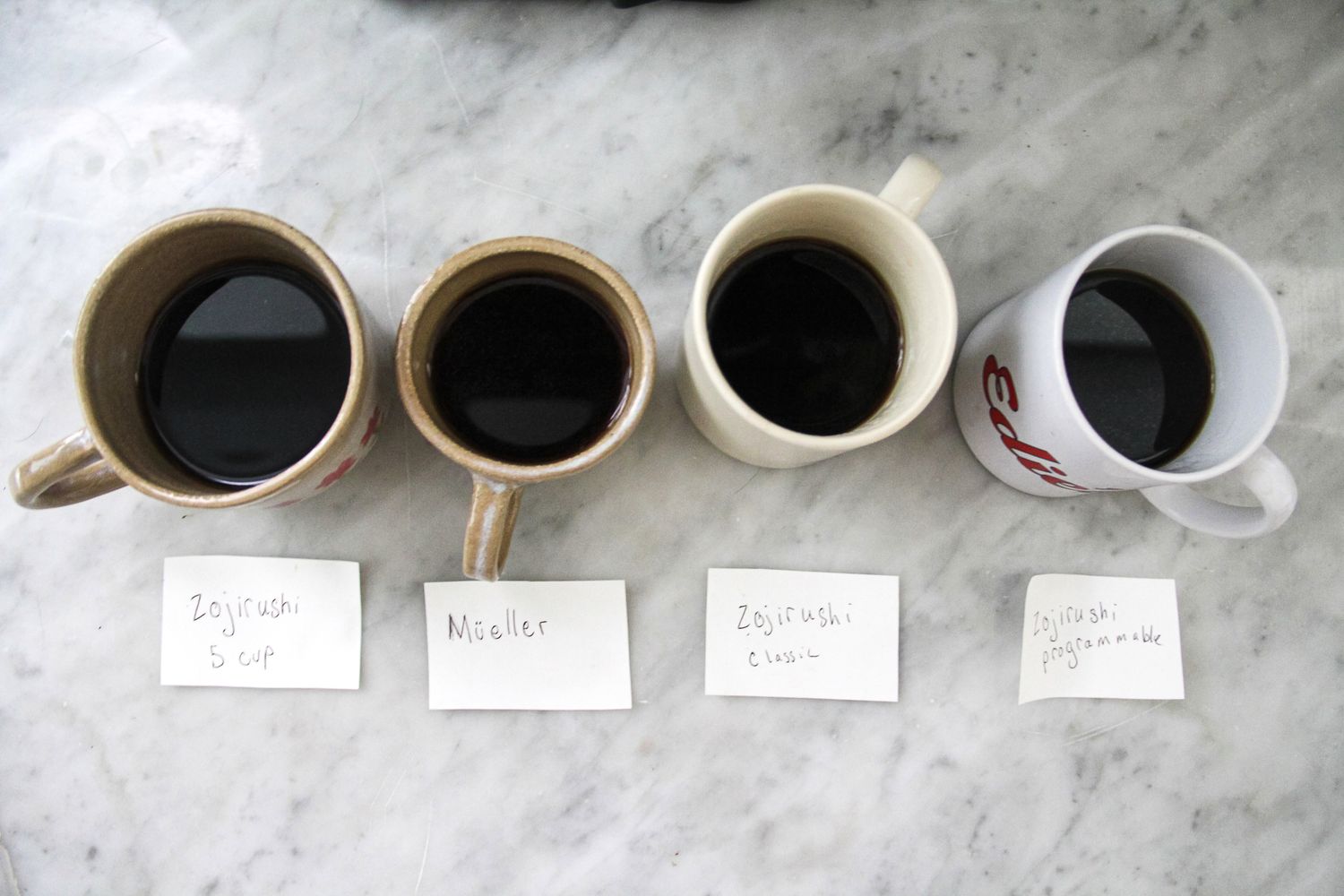 An overhead shot of four coffee mugs with black coffee in them