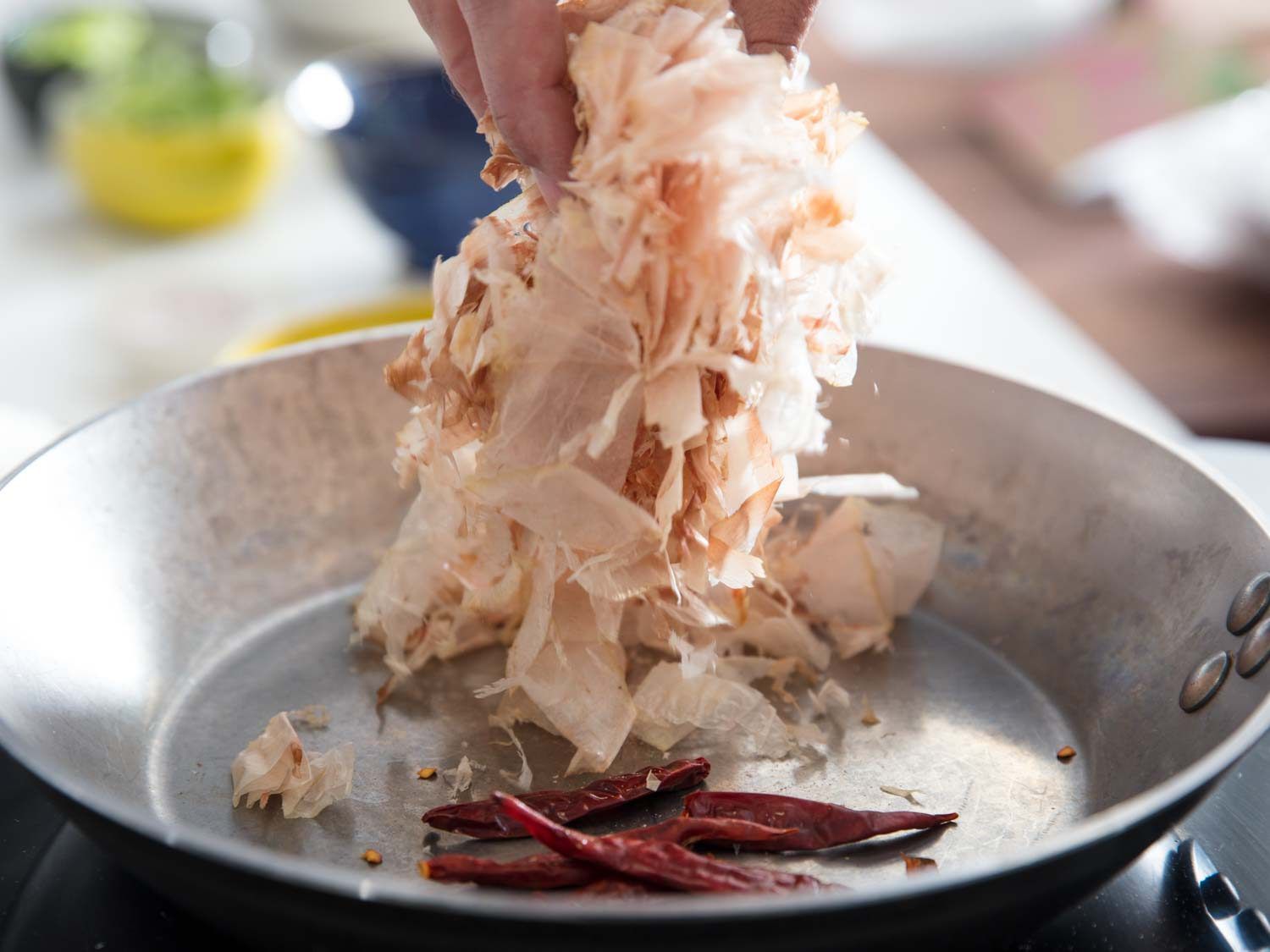 Katsuobushi and dried kashmiri chilies being toasted in a pan for chili gyofun