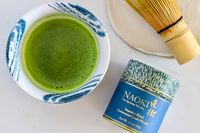 A glass of Naoki Matcha Superior Ceremonial Blend next to the container