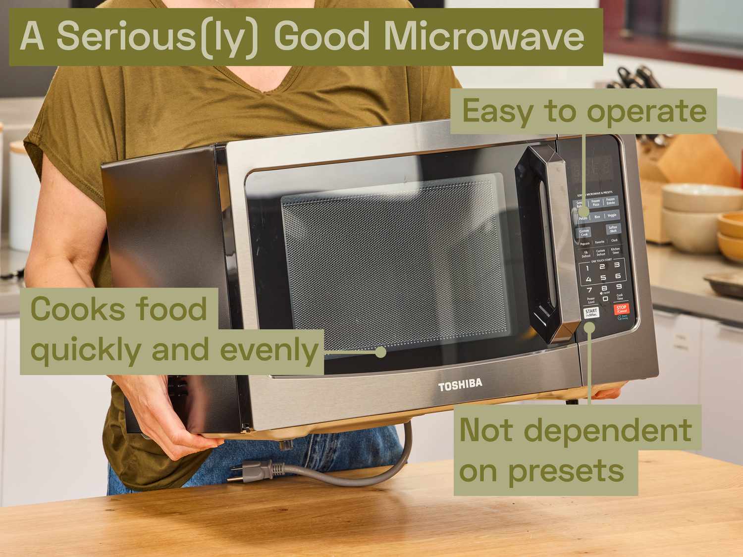 a person carrying the toshiba microwave and setting it on a wooden countertop