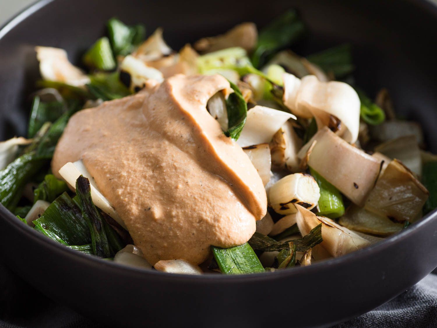 A bowl of Catalonian-Inspired Grilled Vegetable Salad (Xató), made with endive and spring onions and dressed in a romesco-like sauce