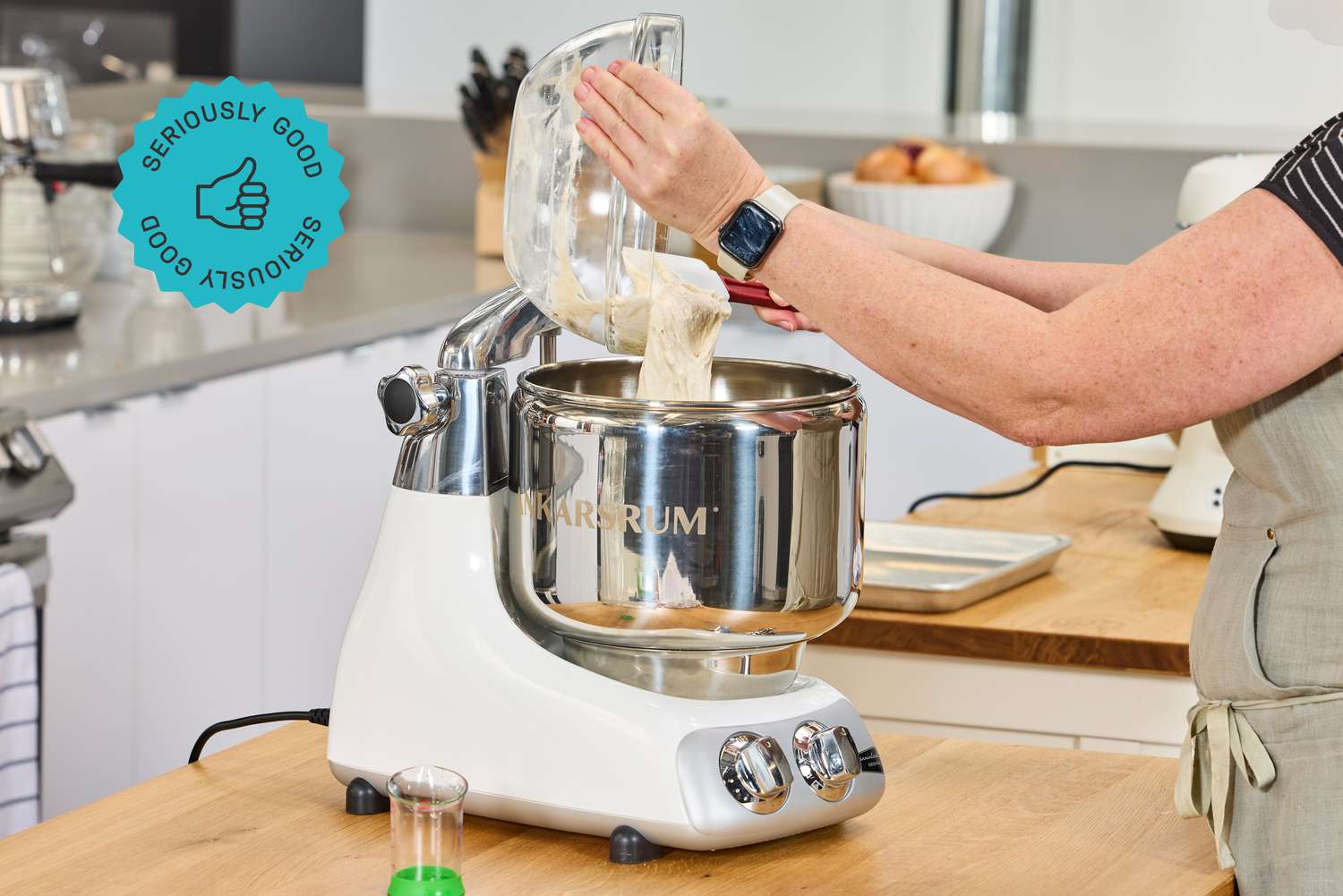 A person adding dough to an Ankarsrum stand mixer.
