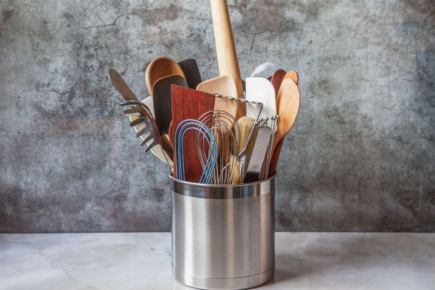 Numerous tools in a stainless steel utensil crock.
