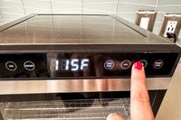 A person setting the temperature of the Cosori food dehydrator