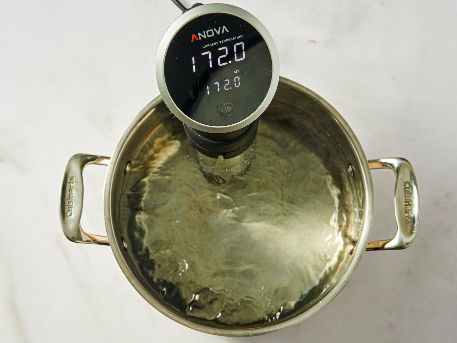 A sous vide immersion circulator in a pot of water displaying a temperature of 1720F