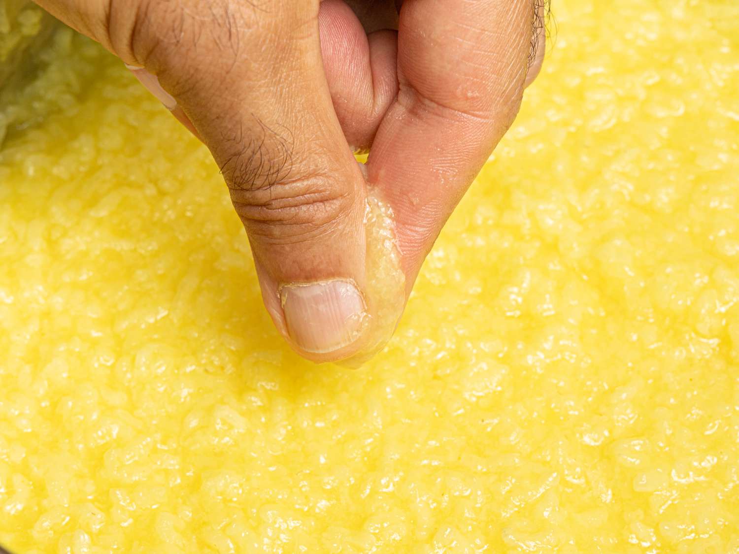 Pressing of rice between two fingers to show consistency 