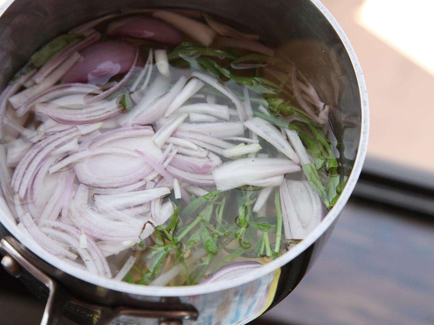 A pot of sliced shallots, tarragon, wine, vinegar, and peppercorns.
