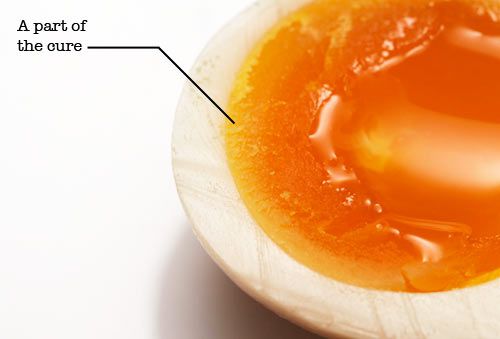 A soft-boiled egg marinated for three days and cut in half to show that the cure has reached the yolk, turning it hard.