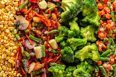 Assorted frozen vegetable pieces including broccoli corn and mixed vegetables arranged in bands