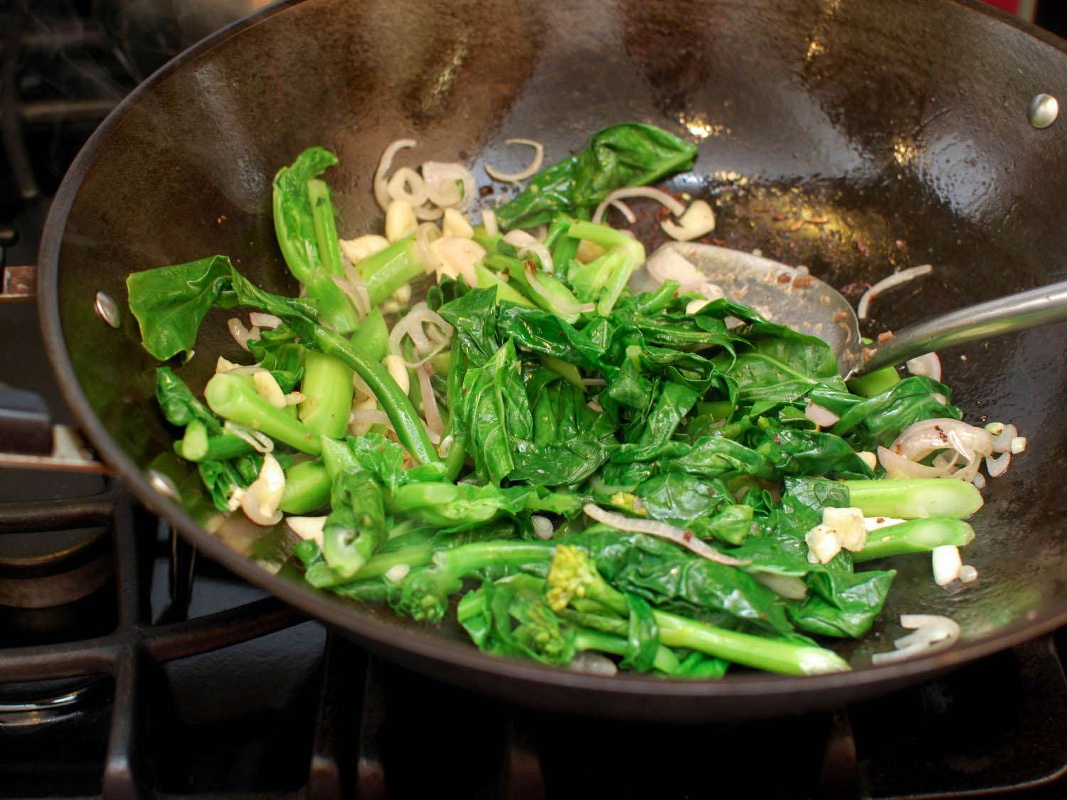 Gai lan, garlic and shallots stir-fried in a wok. 
