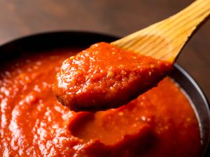 A wooden spoon scooping out a portion of quick and easy Italian-American red sauce that tastes like you spent all day making tomato sauce.