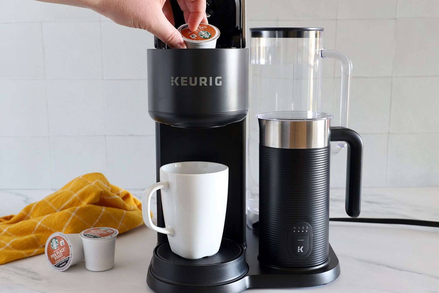 A peron places a K-cup inside a Keurig machine.