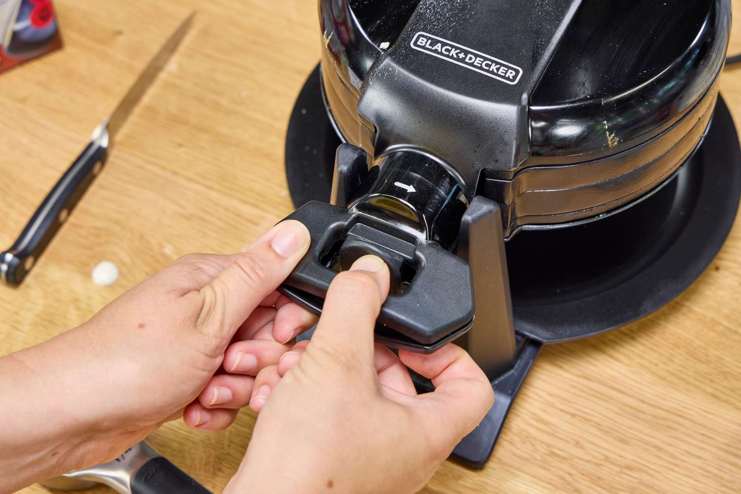 A person locks the Black+Decker Double Flip Rotating Waffle Maker