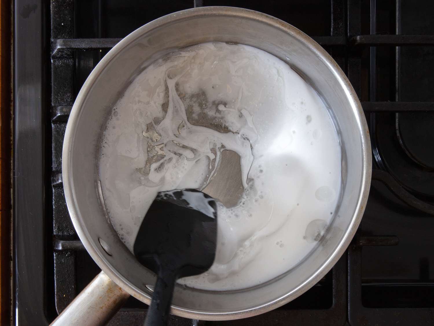 coconut milk added to skillet, beginning to thicken and being stirred with a rubber spatula