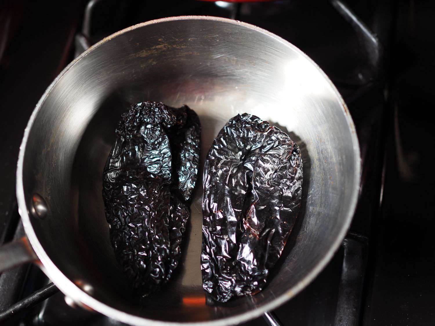Ancho chiles toasting in a skillet.