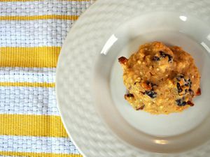 Overhead view of an almond cherry quinoa cookie, served on a white plate.