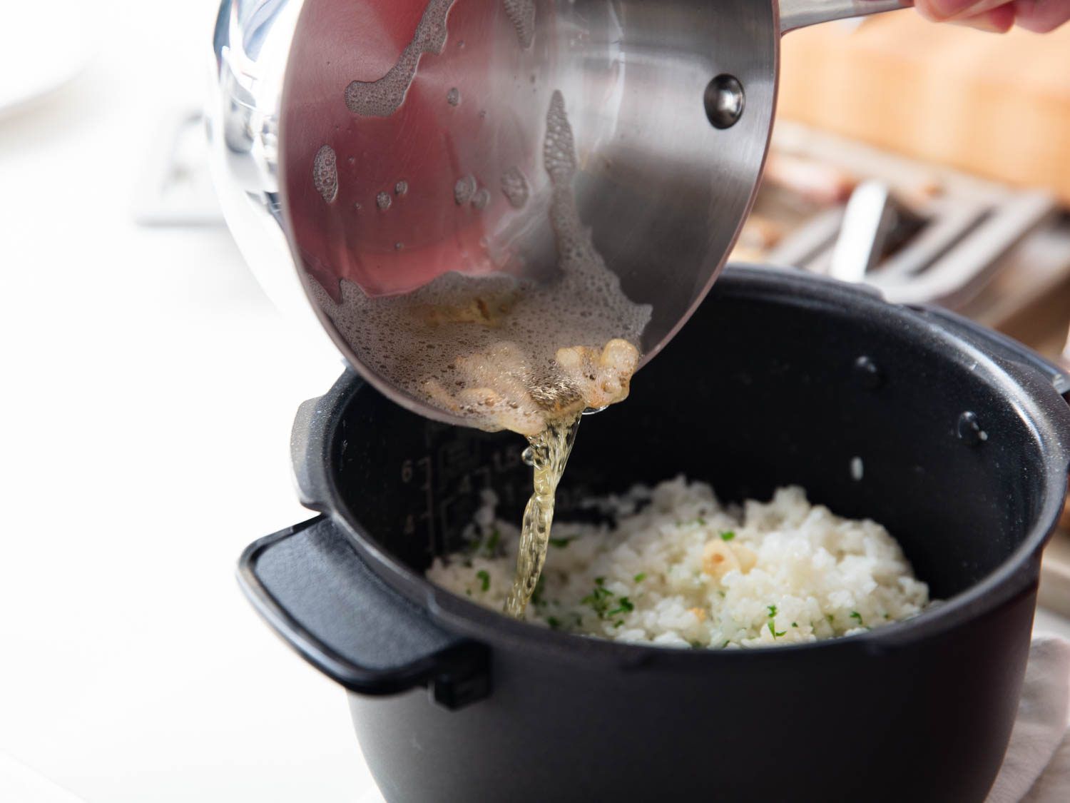 Pouring crispy garlic and duck fat into a pot of rice.
