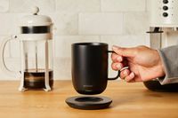 A person lifting the Ember coffee mug off its charging pad