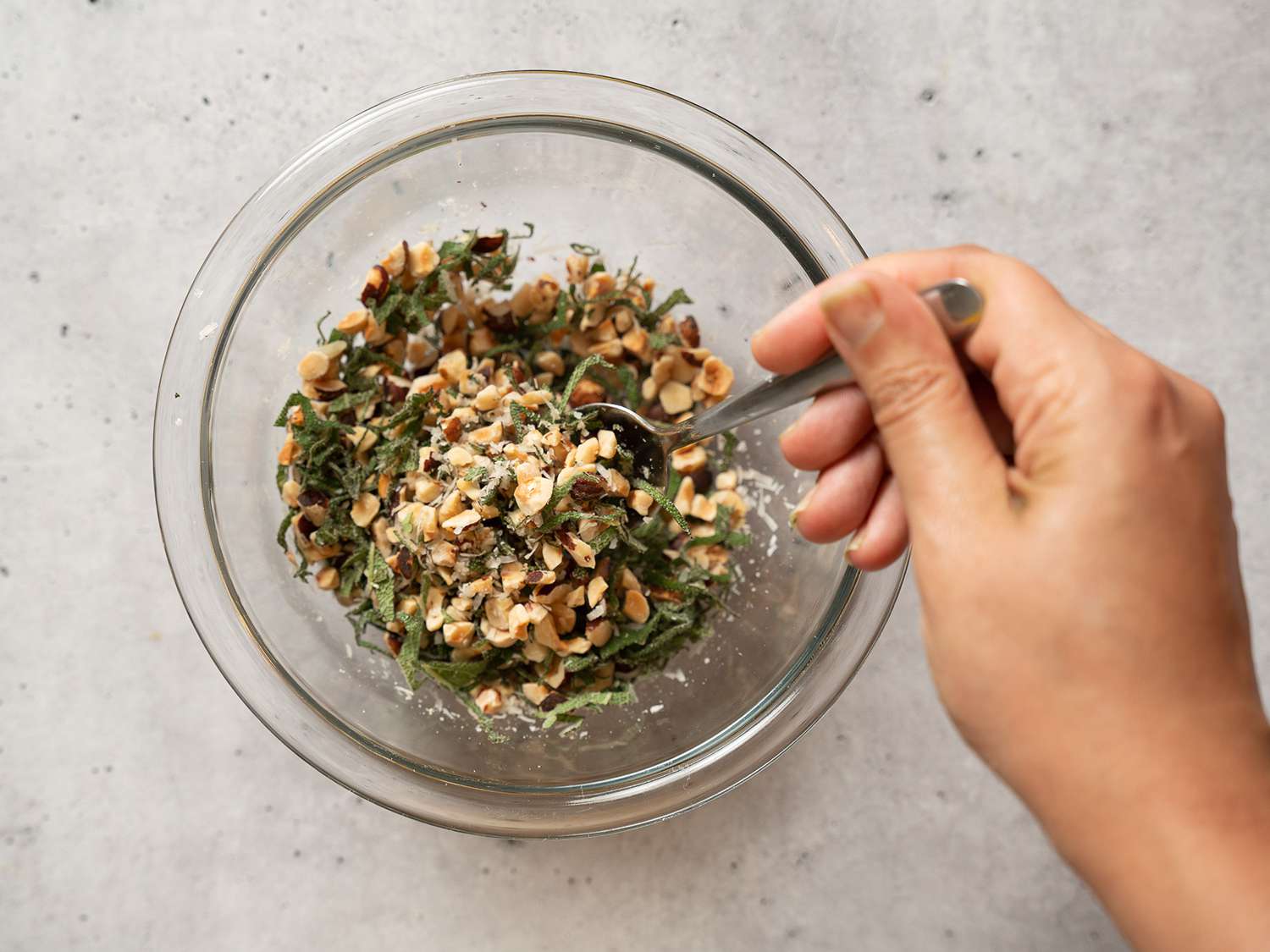 Stirring together chopped hazelnuts, Parmesan, and chopped sage.