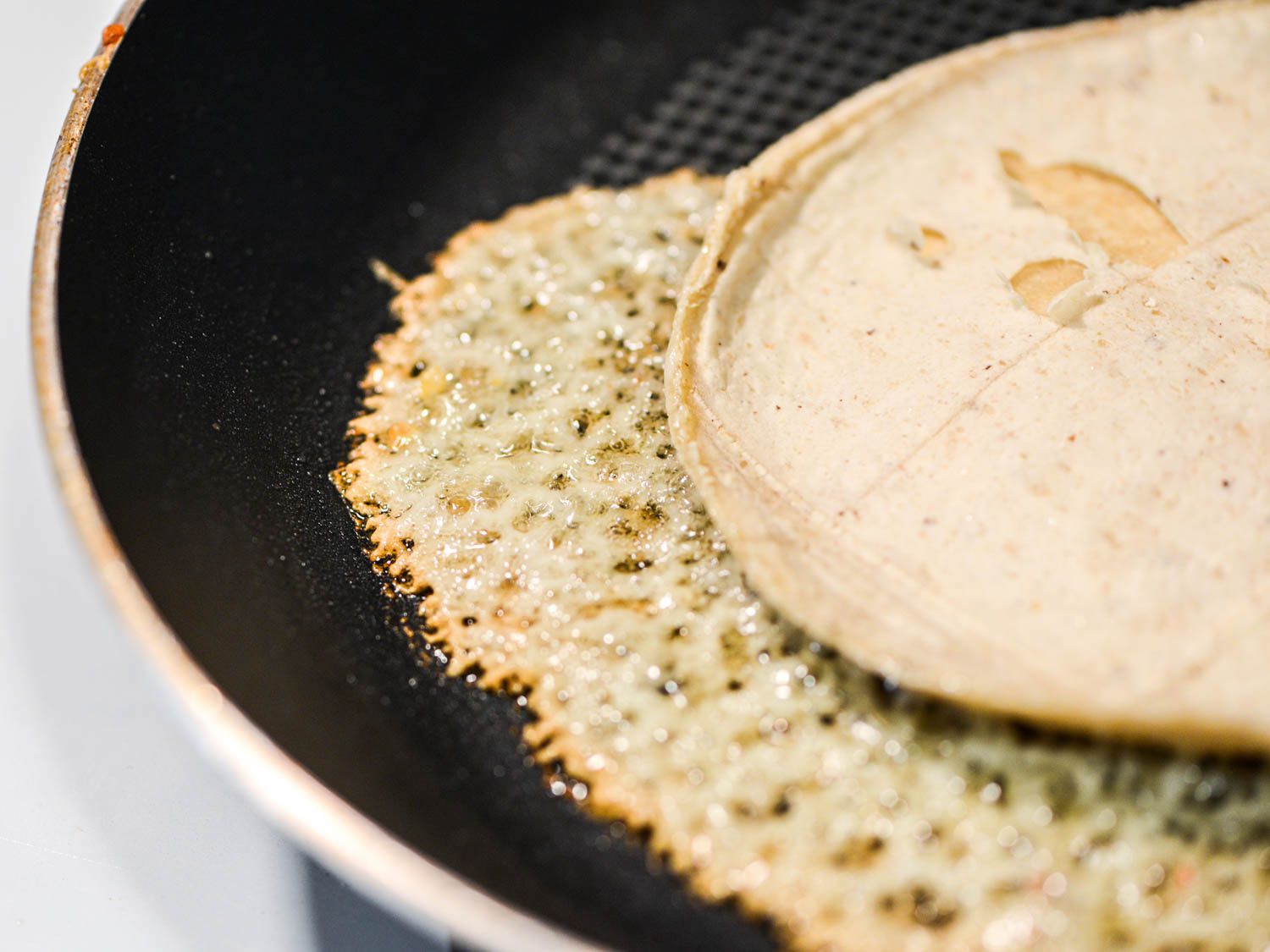 Melted crispy manchego under a tortilla in a nonstick pan.