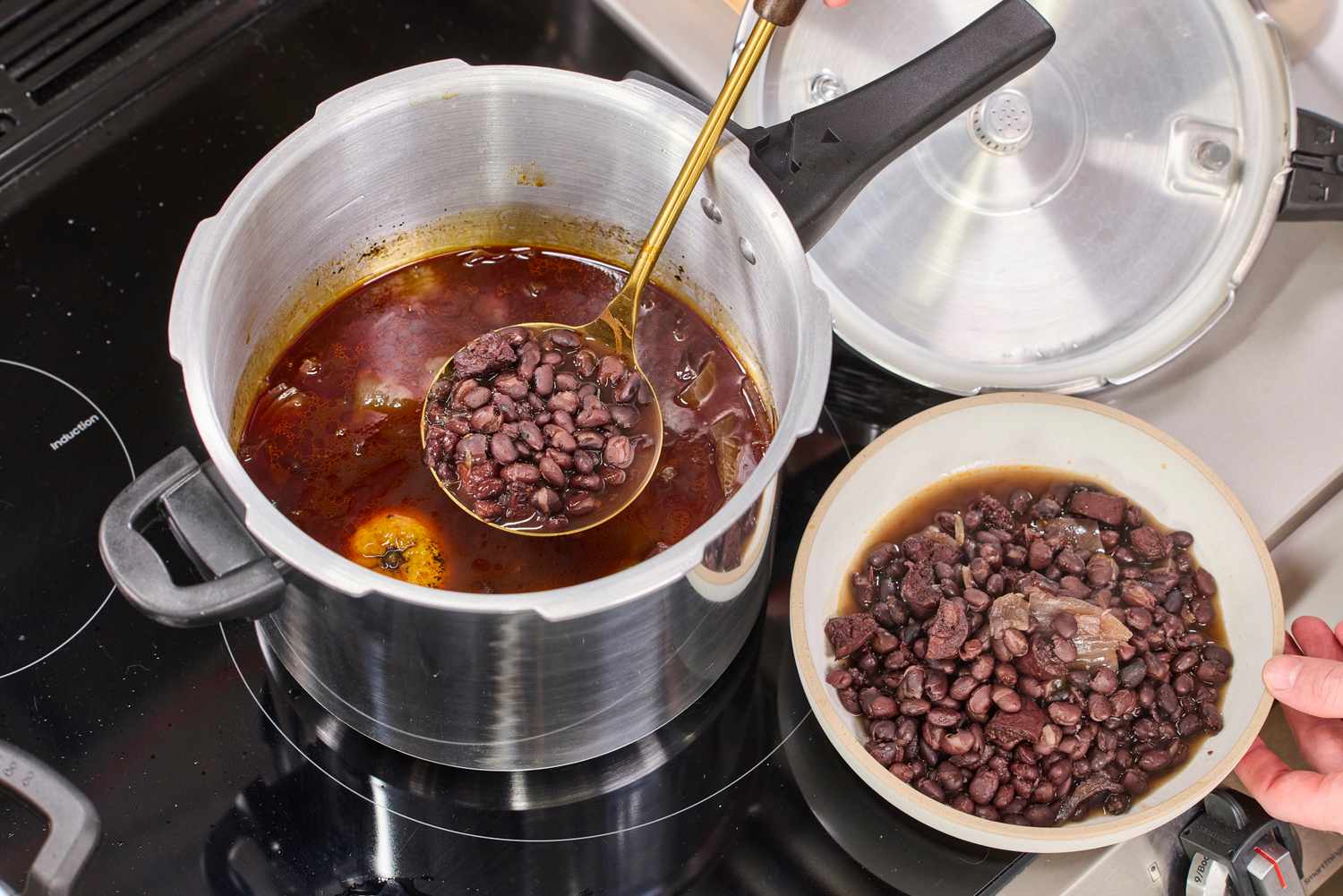 A person spoons beans from the IMUSA 7 Quart Stovetop Aluminum Pressure Cooker