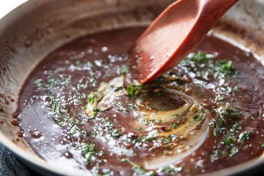 A broken pan sauce being stirred with a wooden spoon.