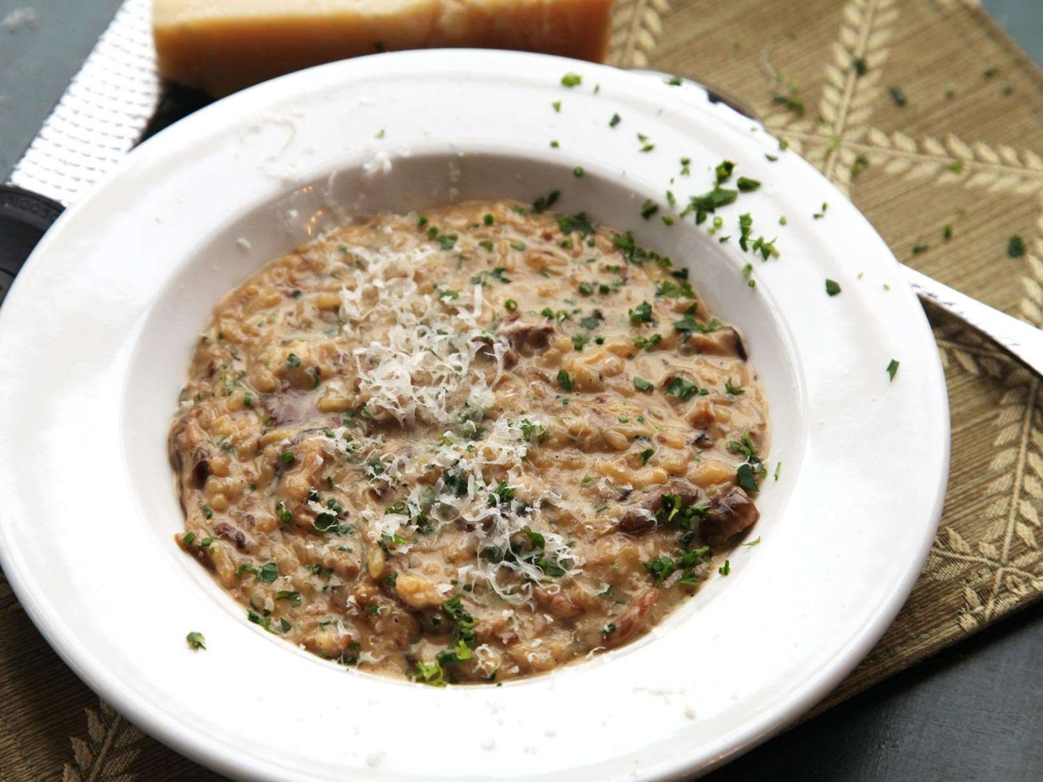 A shallow white bowl filled with creamy mushroom risotto
