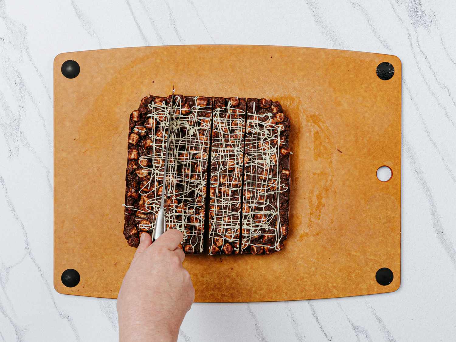 Cutting rocky road into squares on a cutting board, on a marble surface 