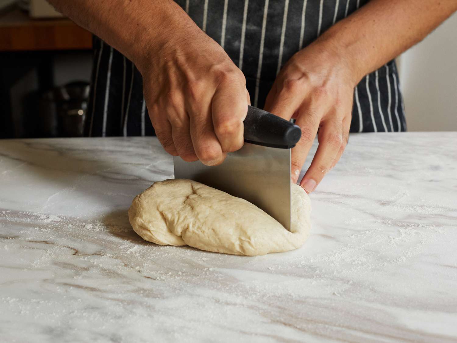 A person cutting pasta using the OXO Bench Scraper