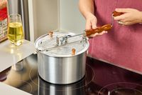 A person turns the crank on the Wabash Valley Farms Original Whirley-Pop Popcorn Popper Stainless Steel